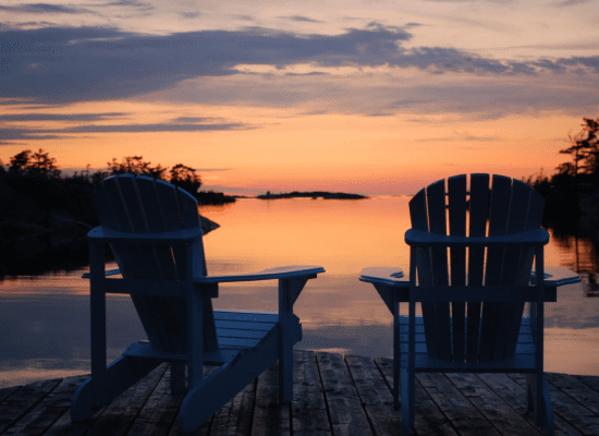Two chairs facing serene sunset waters